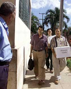 PROJECT VARELA ARRIVES: A security guard Friday observes Cuban activists, left to right, Oswaldo Paya Sardina, Andres Regis Iglesias and Antonio Diaz deliver 11,020 signatures from the Project Varela campaign to Cuba's National Assembly.